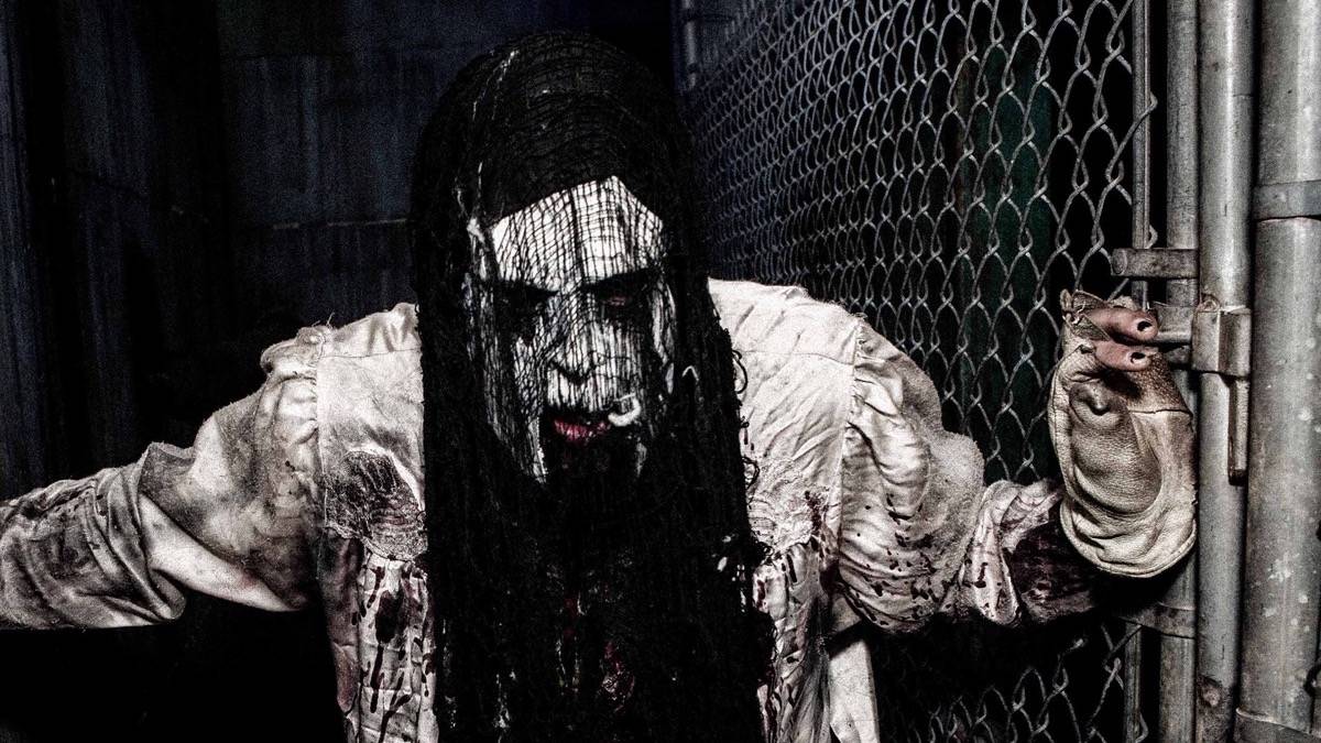 Actor in a scary costume next to a chainlink fence